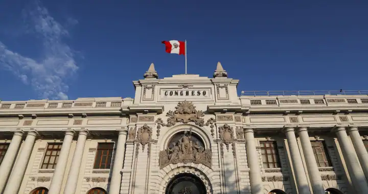 Edificio del Congreso de Perú con bandera peruana, arquitectura colonial, sede del poder legislativo peruano, monumento histórico en Lima.