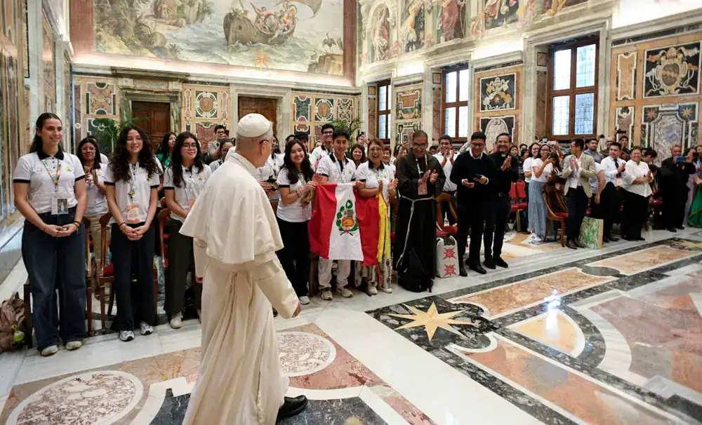 Estudiantes y religiosos en ceremonia dentro de un templo histórico con decoraciones artísticas en las paredes.