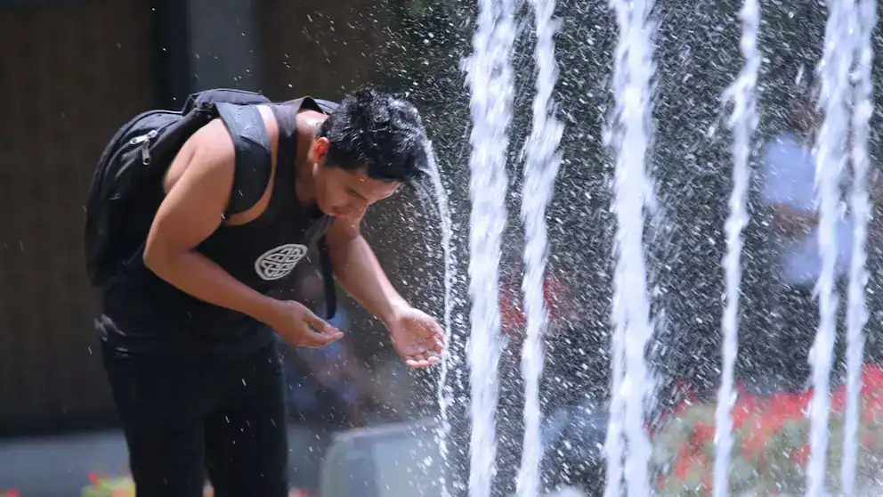 Refrescándose en fuente urbana en Loreto Noticias, imagen de un joven en verano.