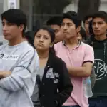 Jóvenes en fila, esperando en una fila, en un entorno urbano, con expresión de incertidumbre, en un contexto social y cultural en Loreto, Perú, resaltando temas de juventud, comunidad y cotidianeidad.