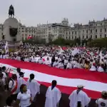 Grandes manifestantes en la Plaza Mayor de Lima con bandera peruana, participando en marcha patriotica por la independencia del Perú.