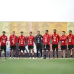 Jugadores de fútbol de Perú en entrenamiento, equipo nacional vistiendo camisetas rojas durante la práctica en el campo deportivo.