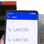 3. Muestra un teléfono móvil con saldo en una app bancaria en Loreto, Perú, en un entorno urbano con edificios modernos y oficinas, reflejando temas de economía y finanzas en la región.