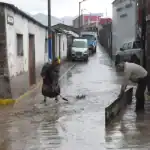 Personas trabajan en calles inundadas en Loreto, Perú, enfrentando lluvias intensas y desbordes de agua en zonas urbanas, afectando residentes y tránsito.