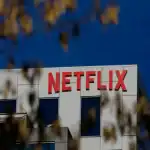 Imagen del logo de Netflix en un edificio moderno con fondo de cielo azul despejado.